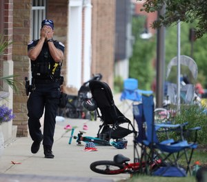 A Lake Forest, Ill., police officer walks down Central Ave in Highland Park, Ill., on Monday, July 4, 2022, after a shooter fired on the suburb's Fourth of July parade.