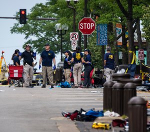 Members of the FBI's Evidence Response Team Unit investigate in downtown Highland Park, Ill., the day after a deadly mass shooting on Tuesday, July 5, 2022.