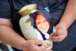 Kelly Titchenell sits on her porch in Mather, Pa., holding a photo of her mother Diania Kronk, and an urn containing her mother's ashes.