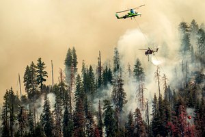 Seen from unincorporated Mariposa County, Calif., a helicopter drops water on the Washburn Fire burning in Yosemite National Park on Saturday.