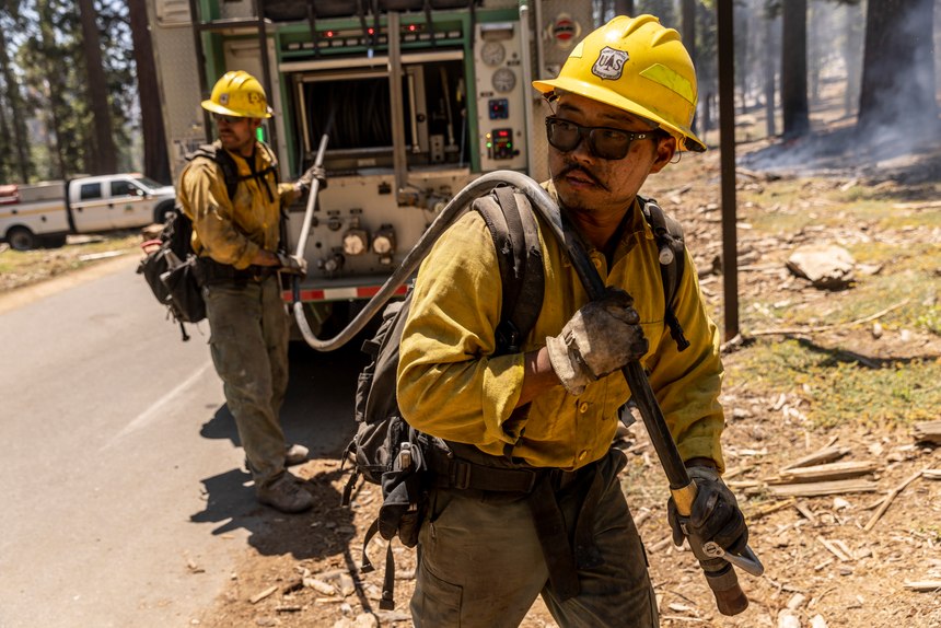 Firefighter Matt Shibuya, right, and assistant engine operator John Carter with the U.S. Forest Service Cleveland National Forest unit, draw a hose to mop up hotspots in Mariposa Grove while battling the Washburn Fire in Yosemite National Park, Calif. Monday, July 11, 2022.