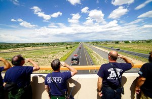 Santa Fe County La Cienega District Firefighters salute as a procession carrying the four victims of a Bernalillo County Sheriff's Office helicopter crash heads south on Interstate 25 on Sunday near Las Vegas, N.M.
