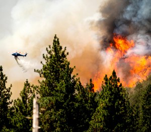 A helicopter drops water while battling the Oak Fire in Mariposa County, Calif., on Sunday, July 24, 2022.