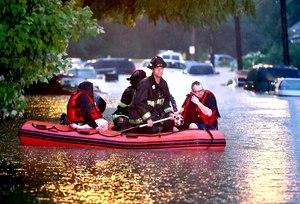 St. Louis firefighters used a boat to rescue people from their flooded homes on Hermitage Avenue in St. Louis on Tuesday. Steven Bertke and his dog, Roscoe, were taken to dry land.