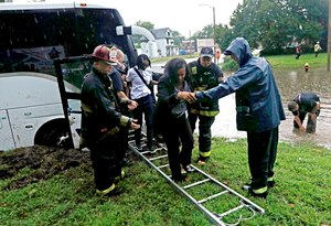 St. Louis Firefighters with Engine House NO 10 assisted a group of adults and students off a bus that got stuck in rising flood waters on Thursday at the intersection of Marcus and Page Avenues in St. Louis, Mo. The group of was en route to the National Association of Black Accountants conference at the University of Missouri St. Louis.