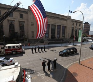 Firefighters salute as the hearse goes by them on South Avenue in Rochester, N.Y., to head toward the cemetery following the funeral for Rochester Police Officer Anthony Mazurkiewicz.