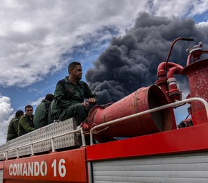 Firefighters move in a truck inside the Matanzas supertanker base to douse a fire that started during a thunderstorm, in Matanzas, Cuba, Sunday, Aug. 7, 2022.