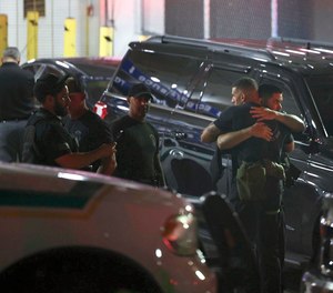 Police officers and other officials stand outside the Ryder Trauma Center after a Miami-Dade police officer was shot.