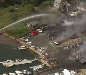 Crews battle a massive fire that destroyed buildings, cars and vessels at a boat yard in Mattapoisett, Mass., on Friday.