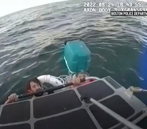 In this image taken from Boston Police Department video, the department’s harbor patrol unit rescues a father and son clinging to a cooler after their boat sank in Boston Harbor on Wednesday, Aug. 24, 2022.