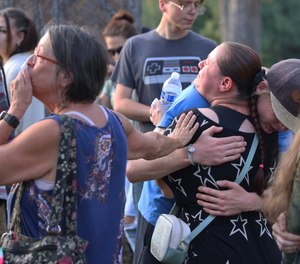 People gather in Drake Park for a vigil in honor of the community members killed in Sunday's shooting at the Forum shopping center.