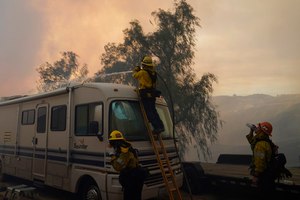 Firefighters pour water over a camper while battling the Route Fire on Wednesday in Castaic, Calif.
