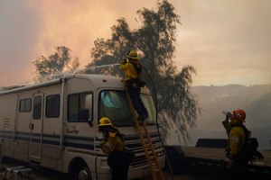 Firefighters pour water over a camper while battling the Route Fire on Wednesday in Castaic, Calif.