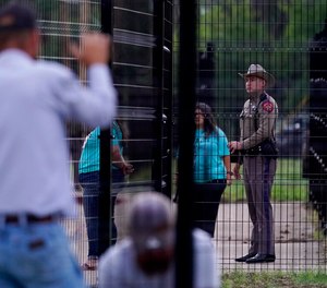 A Texas State Trooper keeps watch as students arrive at Uvalde Elementary for the first day of school and workers continue construction on a new fence, Tuesday, Sept. 6, 2022, in Uvalde.