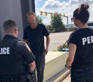 Chesterfield Patrol Officer Travis Adams, left, and peer recovery specialist Joy Bogese, right, talk with Adam Hall as part of Project Recover, in Chesterfield County, Va., Monday, Aug., 29, 2022.