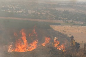Firefighters watch as the Fairview Fire burns on a hillside Thursday near Hemet, Calif.