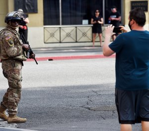 A pedestrian photographs a U.S. National Guardsman.