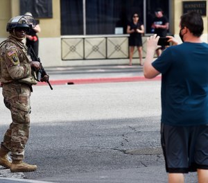 A pedestrian photographs a U.S. National Guardsman.