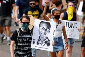 A demonstrator carries an image of Elijah McClain during a rally and march in Aurora, Colo., on June 27, 2020. A Colorado judge on Friday responded to a request by a coalition of news organizations to release an amended autopsy report for McClain, a 23-year-old Black man who died after a 2019 encounter with police, by ruling the report be made public only after new information it contains is redacted.