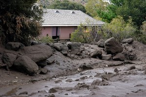 The front yard of a property is covered in mud in the aftermath of a mudslide Tuesday in Oak Glen, Calif. A woman who went missing after flash floods unleashed mudslides that swept through her town in the Southern California mountains was found dead under a pile of mud, rocks and other debris, authorities said Friday.