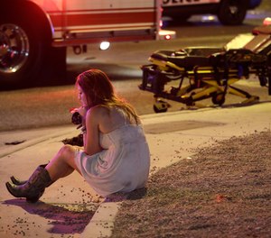 A woman sits on a curb on Oct. 2, 2017, at the scene of a shooting outside a music festival on Oct. 1 that killed 58 people and injured hundreds on the Las Vegas Strip.