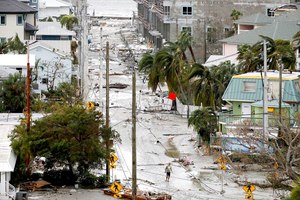 A man walks through a street among damaged homes and businesses and debris in Fort Myers Beach, Fla., on Thursday, following Hurricane Ian.