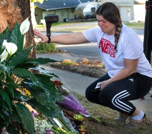 Kayla Kelly grieves as mourners gather and lay flowers and gifts at the site of a deadly car crash during an impromptu memorial service.