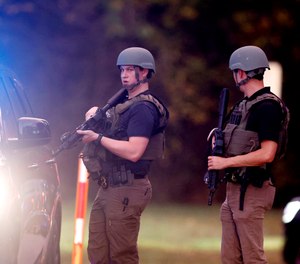 Law enforcement stand at the entrance to Neuse River Greenway Trail parking at Abington Lane following a shooting in Raleigh, N.C., Thursday, Oct. 13, 2022.