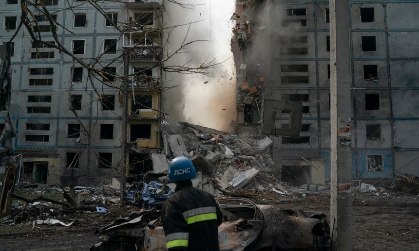 A firefighter looks at a part of a wall falling from the residential building that was heavily damaged after a Russian attack in Zaporizhzhia, Ukraine, Sunday, Oct. 9, 2022.