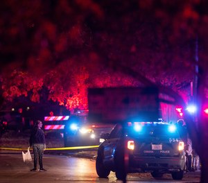 A woman walks by police tape after Omaha police shot a man who drove through a barricaded area during a neighborhood Halloween celebration in Omaha, Neb., late Monday, Oct. 31, 2022.