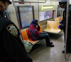 New York Police Department officers wake up sleeping passengers and direct them to the exits at the 207th Street station on the A train.