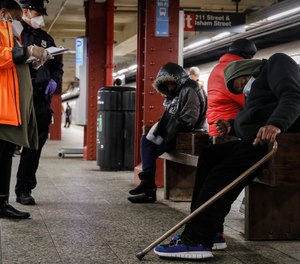 A homeless outreach worker and New York police officer assist passengers found sleeping on subway cars at the 207th Street A-train station, Thursday, April 30, 2020, in the Manhattan borough of New York.