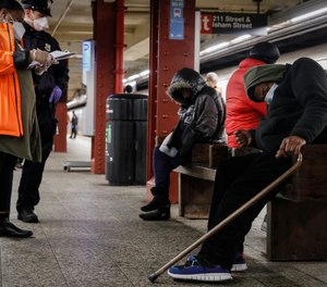 A homeless outreach worker and New York police officer assist passengers found sleeping on subway cars at the 207th Street A-train station, Thursday, April 30, 2020, in the Manhattan borough of New York.