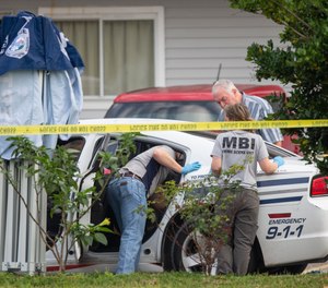 Mississippi Bureau of of Investigations investigators inspected a police vehicle on the scene of the murder of two police officers outside a Motel 6.