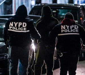 New York City police department officers escort a handcuffed suspect to a car during a raid in the Brooklyn borough of New York.