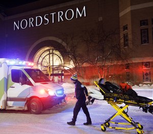 Two first responders and an ambulance are seen at the entrance to Nordstrom at the Mall of America in Bloomington, Minn., after reports of shots fired on Friday, Dec. 23, 2022.