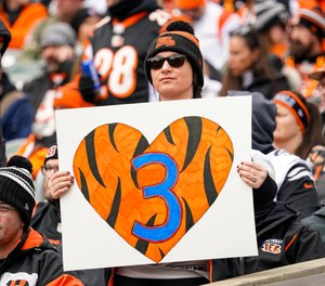 A fan holds a poster honoring injured Buffalo Bills player Damar Hamlin before an NFL football game between the Baltimore Ravens and the Cincinnati Bengals in Cincinnati, Sunday, Jan. 8, 2023.