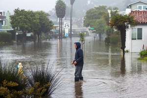 A man wades through a flooded street in the Rio Del Mar neighborhood of Aptos, Calif., on Monday.