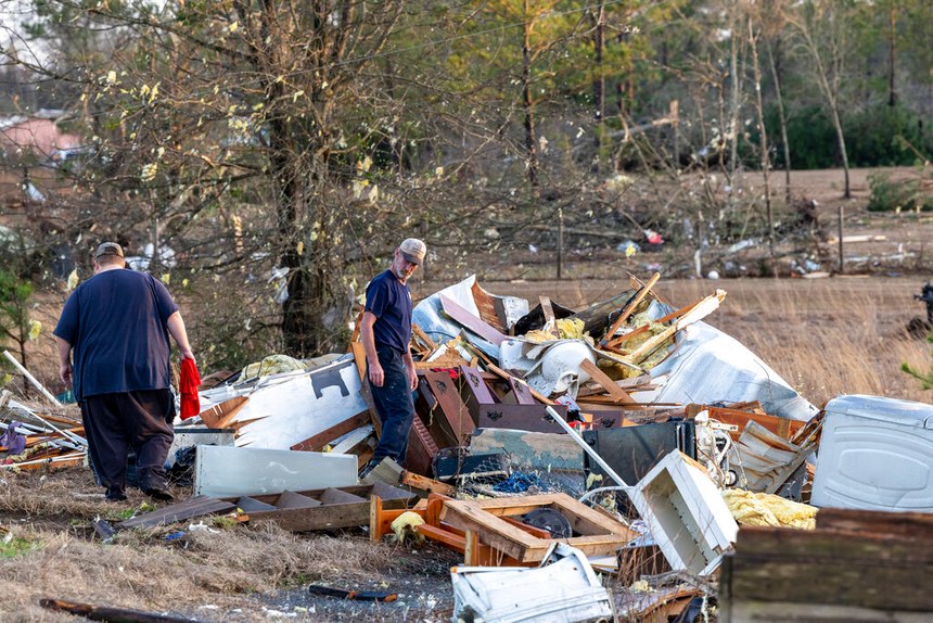 Scott Wayman (center) examines his former rental home in the aftermath of severe weather Thursday in Prattville, Ala. A giant, swirling storm system billowing across the South spurred a tornado that shredded the walls of homes, toppled roofs and uprooted trees in Selma.