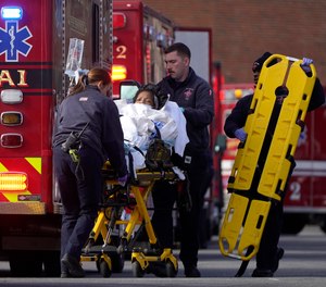 A patient, center, is placed into an ambulance while being evacuated from Signature Healthcare Brockton Hospital, Tuesday, Feb. 7, 2023, in Brockton, Mass.