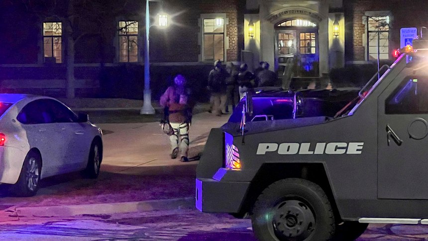 Armed police officers with weapons drawn rush into Phillips Hall on the campus of Michigan State University, in East Lansing, Mich., as authorities respond to reports of shootings, late Monday, Feb. 13, 2023. 