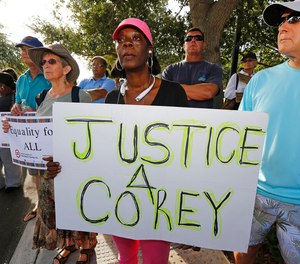Attendees hold signs in support of Corey Jones at a 