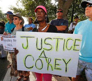 Attendees hold signs in support of Corey Jones at a