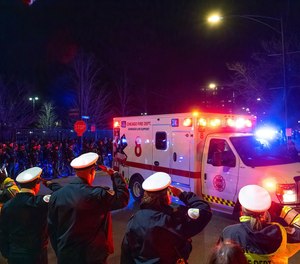 Chicago police officers and firefighters salute a procession carrying the remains of a Chicago police officer who was shot and killed as it arrives at the Cook County Medical Examiner's Office.