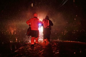Sonoma County Fire's Eric Gromala guides a woman to safety after her vehicle stalled out in deep floodwater on Eastside Road near Forestville, Calif., Friday.
