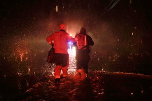 Sonoma County Fire's Eric Gromala guides a woman to safety after her vehicle stalled out in deep floodwater on Eastside Road near Forestville, Calif., Friday.