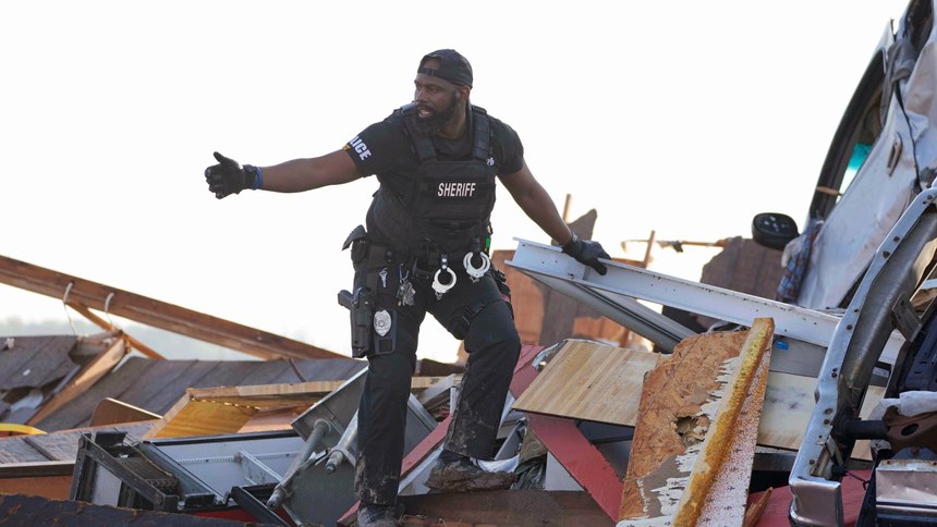 A sheriff's deputy gives the all clear signal after climbing onto a piled up vehicle to search for survivors or the deceased at Chuck's Dairy Bar in Rolling Fork, Miss., Saturday, March 25, 2023.