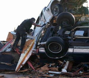 A sheriff's deputy climbs onto a pile of wind-tossed vehicles to search for survivors or the deceased at Chuck's Dairy Bar in Rolling Fork, Miss., Saturday, March 25, 2023. Emergency officials in Mississippi say several people have been killed by tornadoes that tore through the state on Friday night, destroying buildings and knocking out power as severe weather produced hail the size of golf balls moved through several southern states.