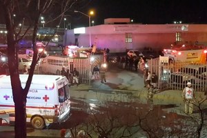 In this image taken from a video, ambulances and rescue team staffers can be seen outside an immigration center in Ciudad Juarez, Mexico, on Tuesday.