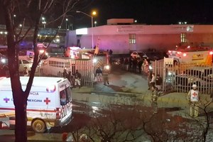 In this image taken from a video, ambulances and rescue team staffers can be seen outside an immigration center in Ciudad Juarez, Mexico, on Tuesday.
